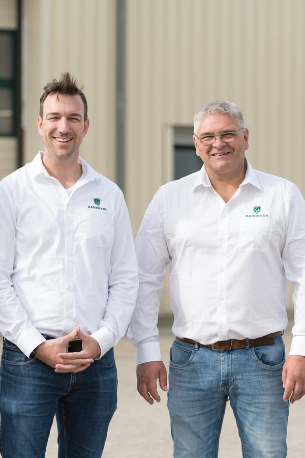 Zeitungscover mit der Geschäftsführung der Firma Hartmann Logistik GmbH vor zwei grünen LKWs stehend.