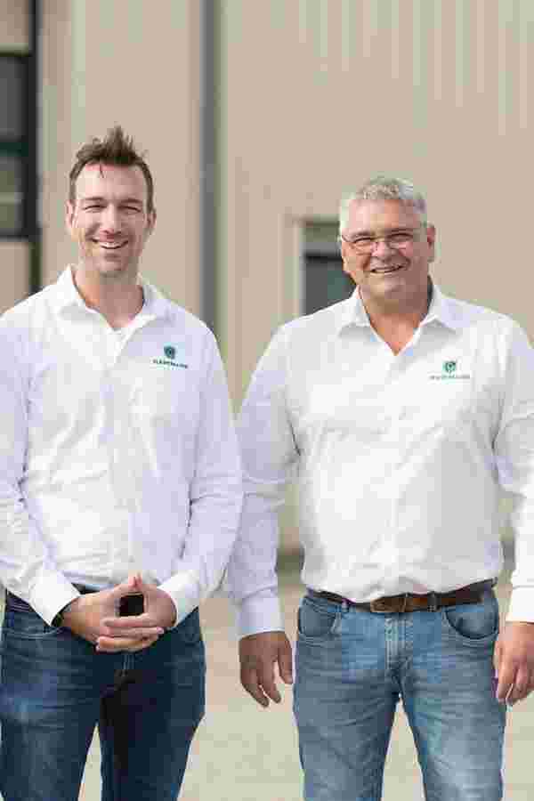 Zeitungscover mit der Geschäftsführung der Firma Hartmann Logistik GmbH vor zwei grünen LKWs stehend.