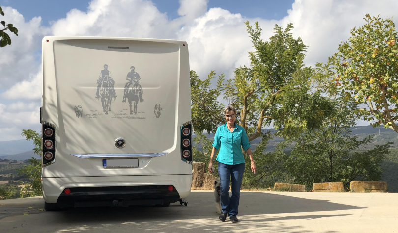 Zufriedene Kundin neben ihrem glänzenden Wohnmobil
